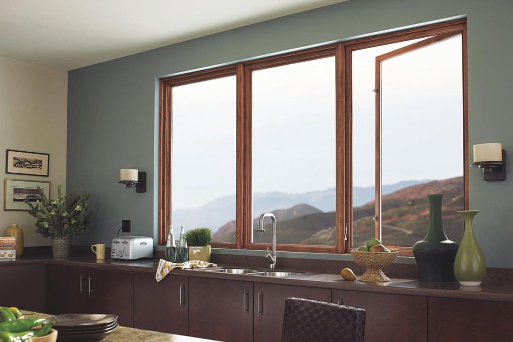 Wood-framed kitchen windows with a hillside view